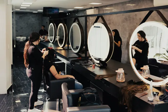 Des miroirs ronds éclairés dans un salon de coiffure.